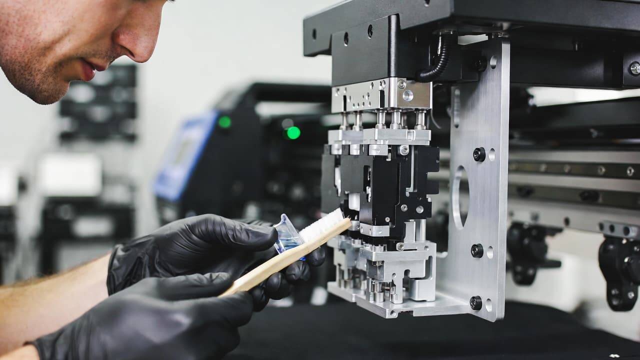 Technician cleaning DTG printer printhead during maintenance routine